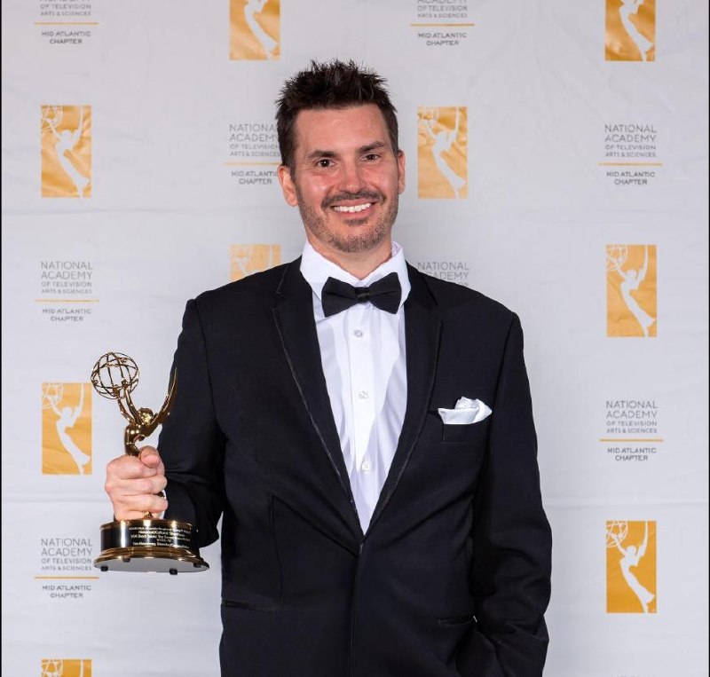 Tim Novotney holding a Mid-Atlantic Emmy Award